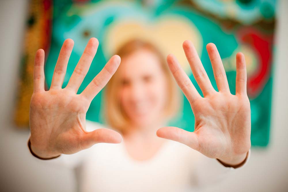 Christina Koch hält ihre Handinnenflächen ausgestreckt in die Kamera. Ihr Gesicht ist da im Hintergrund und verschwommen